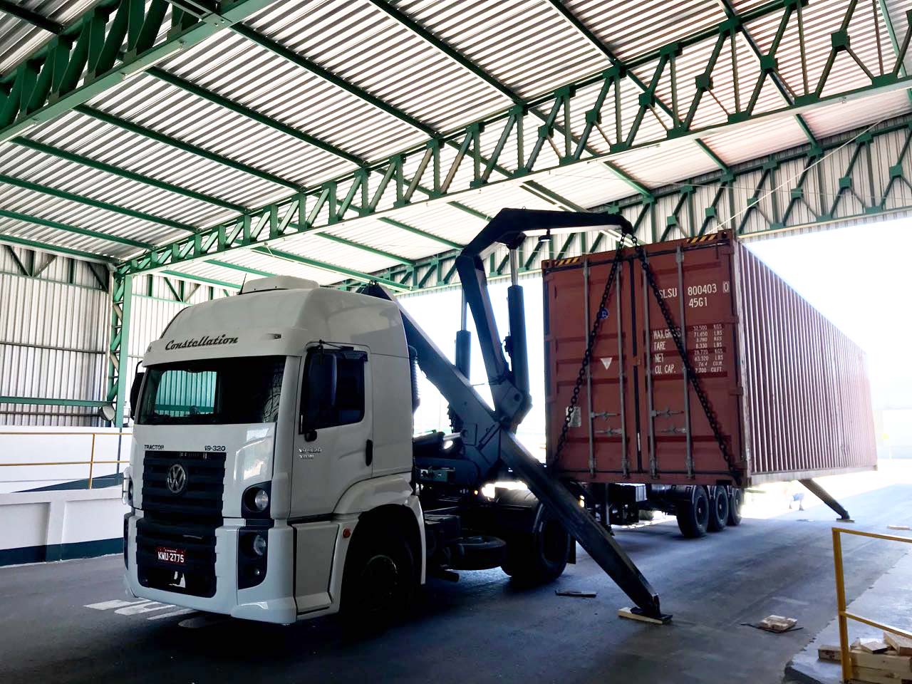 Truck with hydraulic arm unloading cargo container