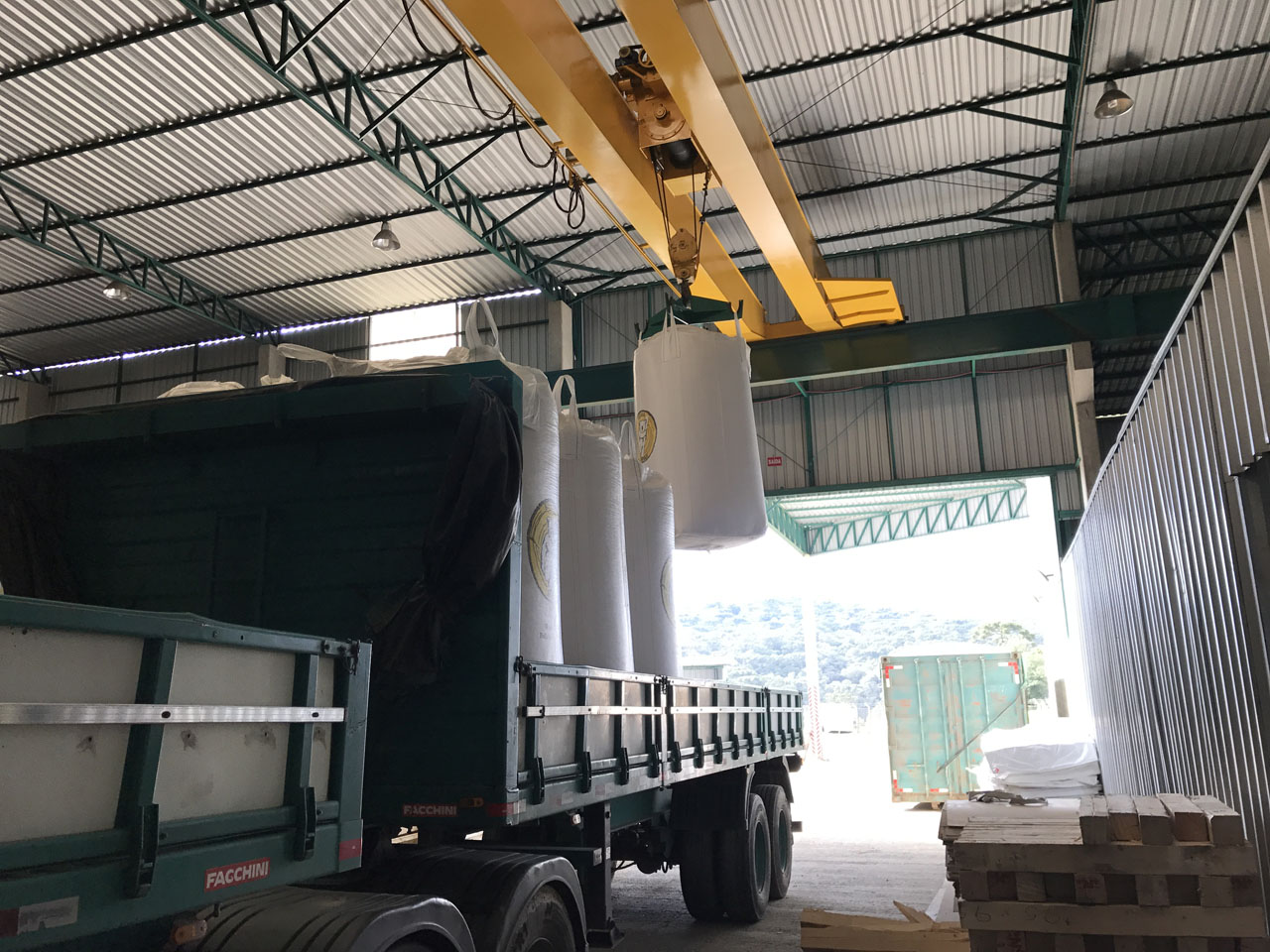Overhead crane loading the truck with white batches of cargo